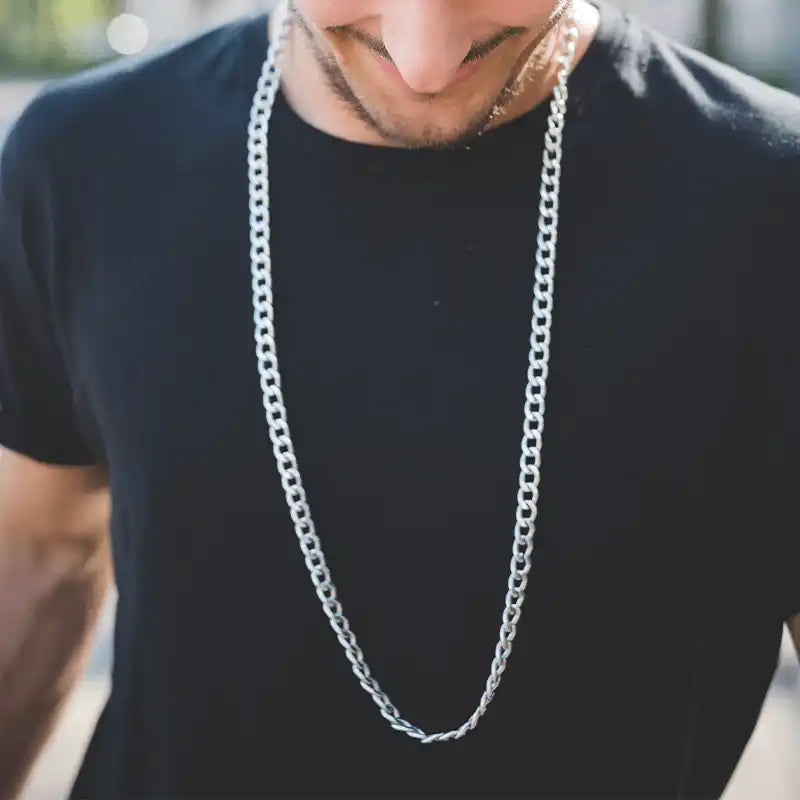 Silver chain necklace worn over a black t-shirt.