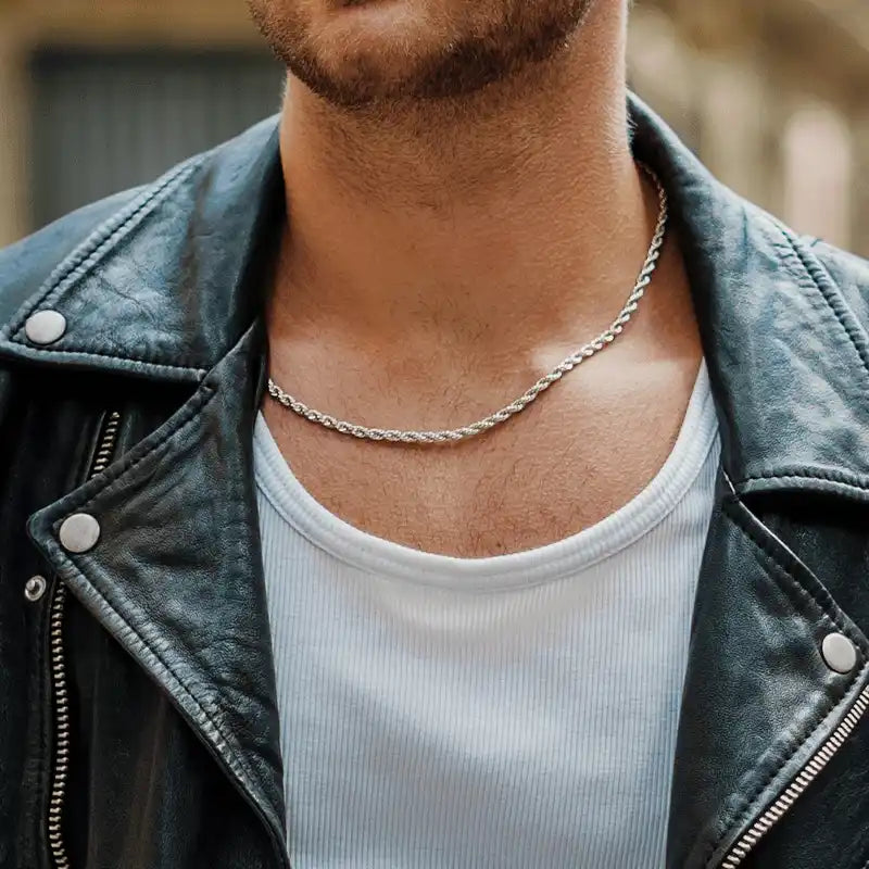 Silver rope chain necklace worn with a leather jacket and white tank top.