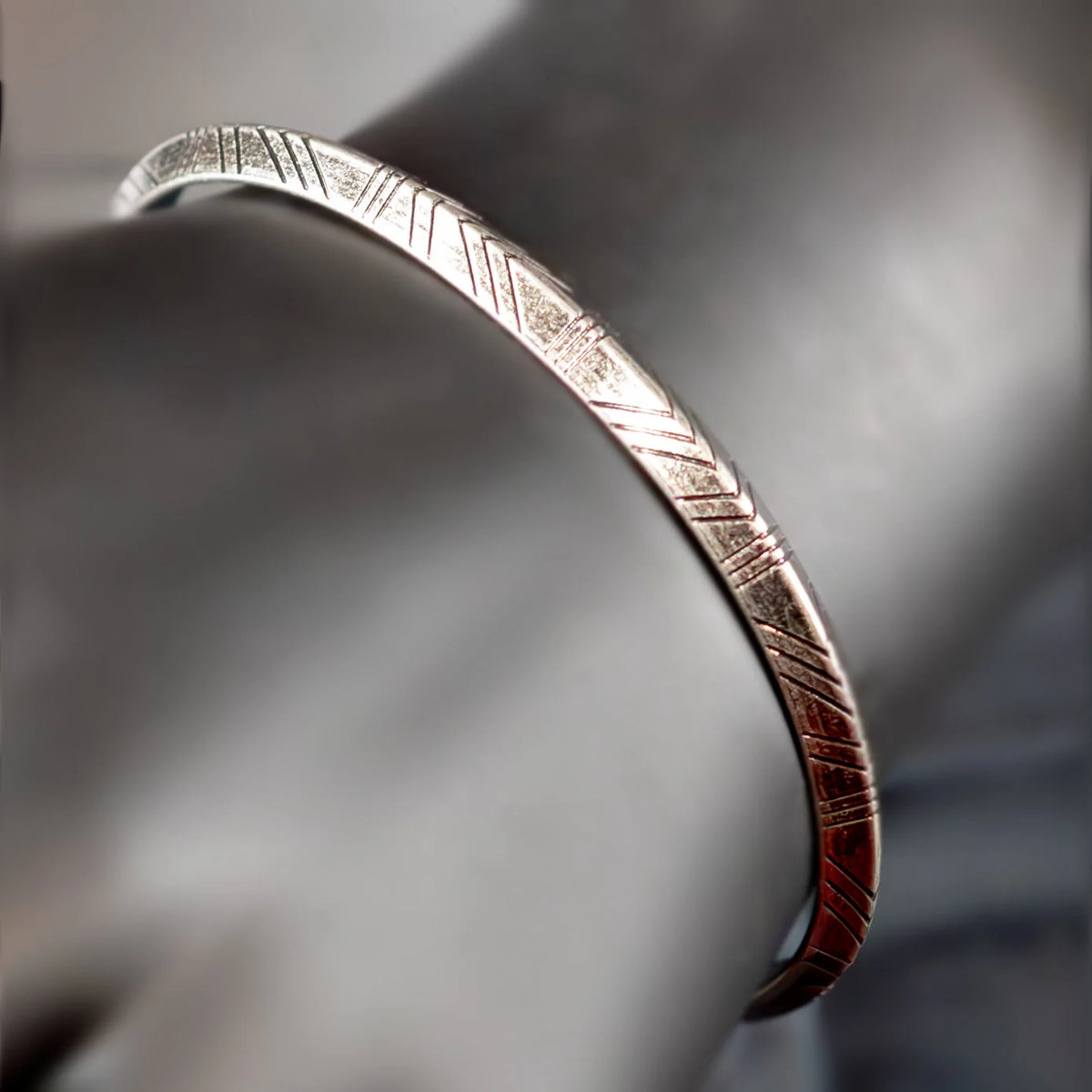 Silver bracelet with etched geometric patterns.