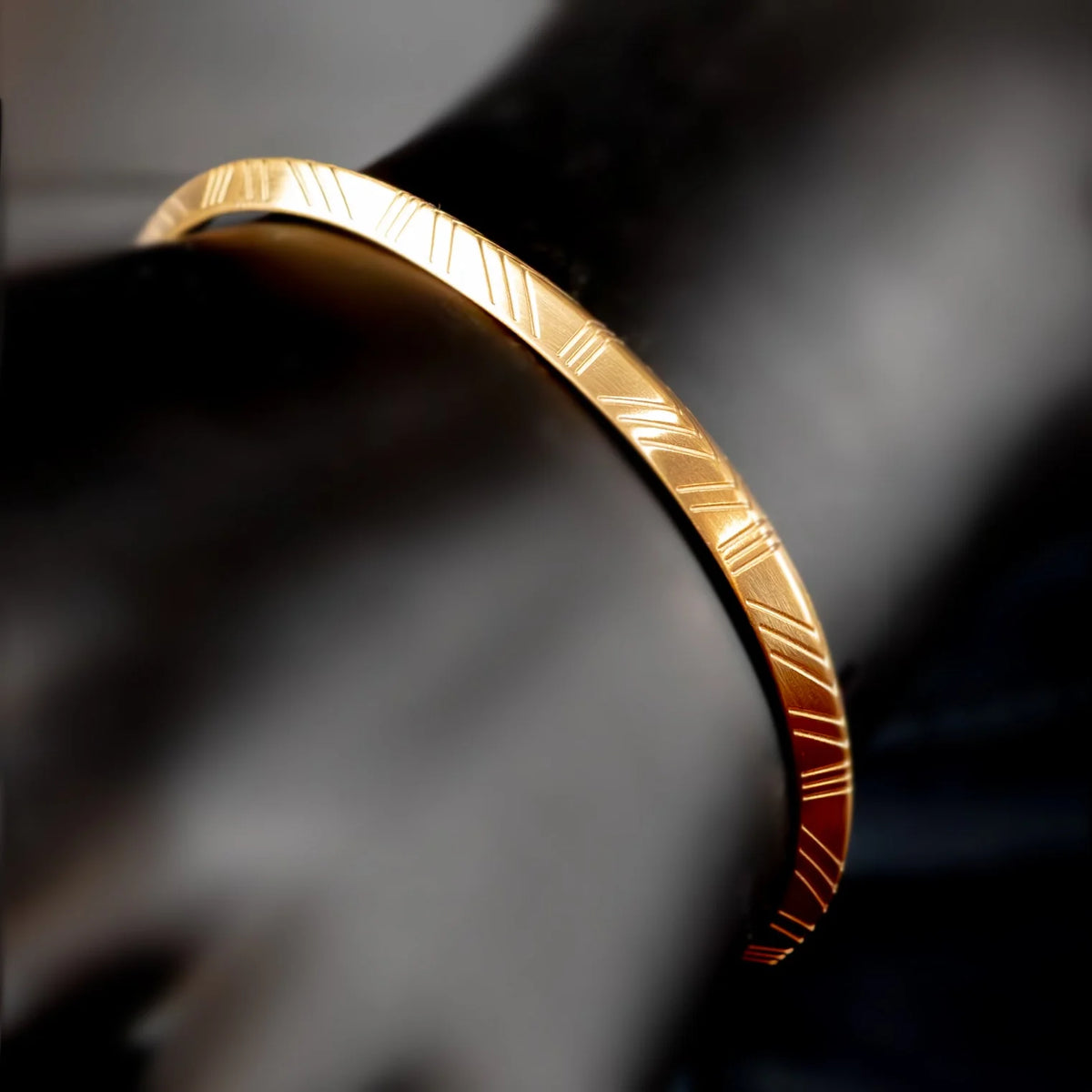 Gold bangle bracelet with engraved linear pattern.