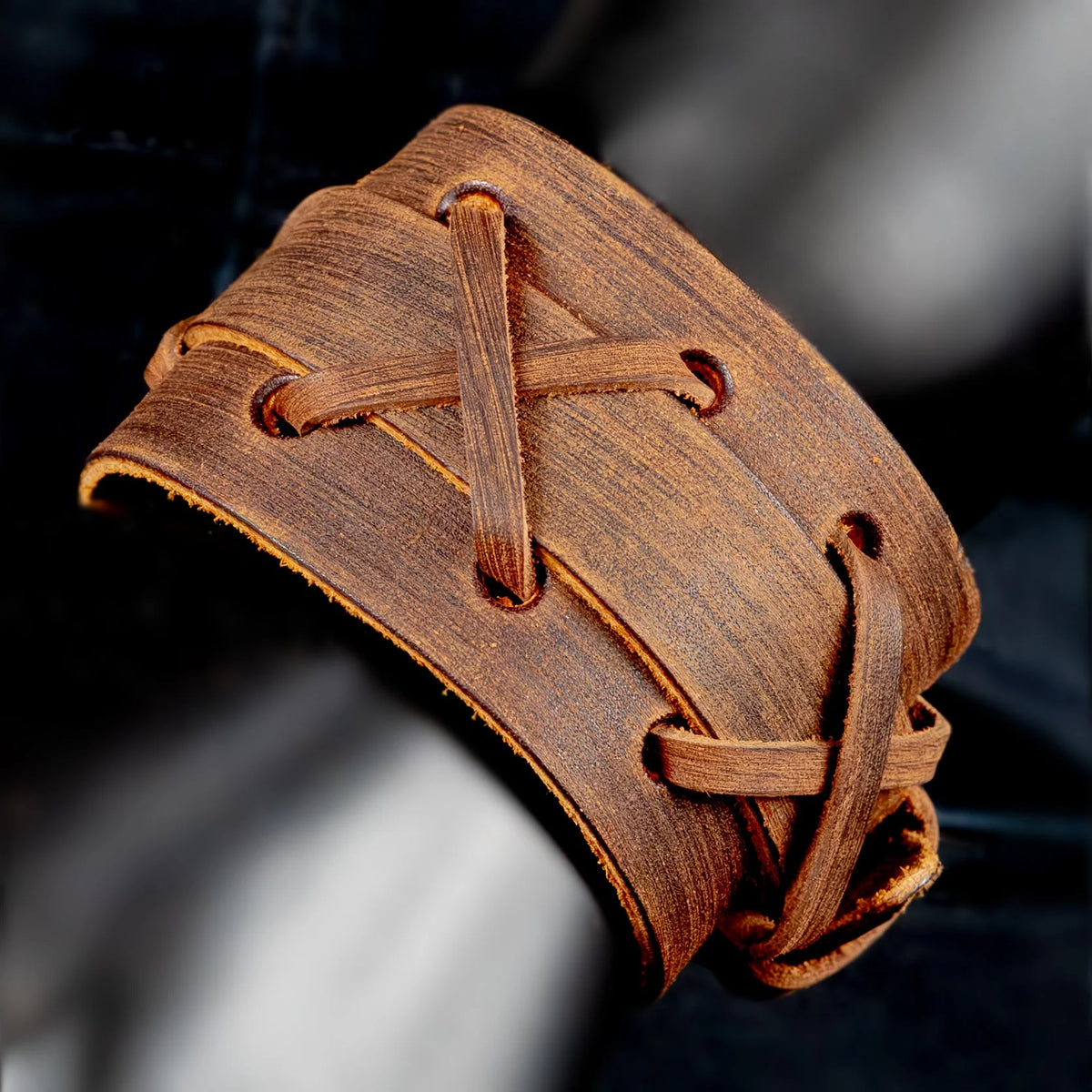 Leather cuff bracelet with laced design and rustic appearance.