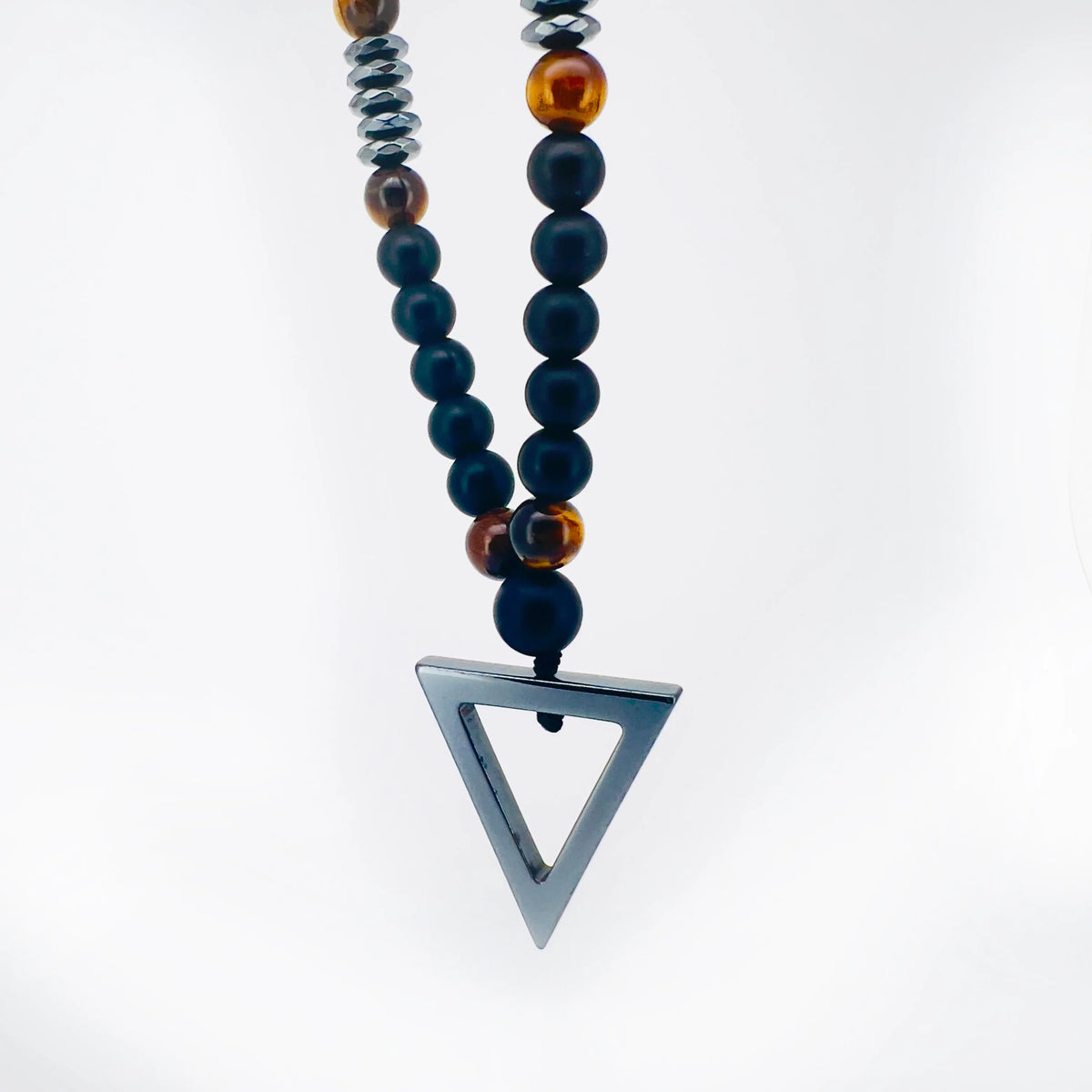 Necklace with dark beads and a triangular metal pendant.