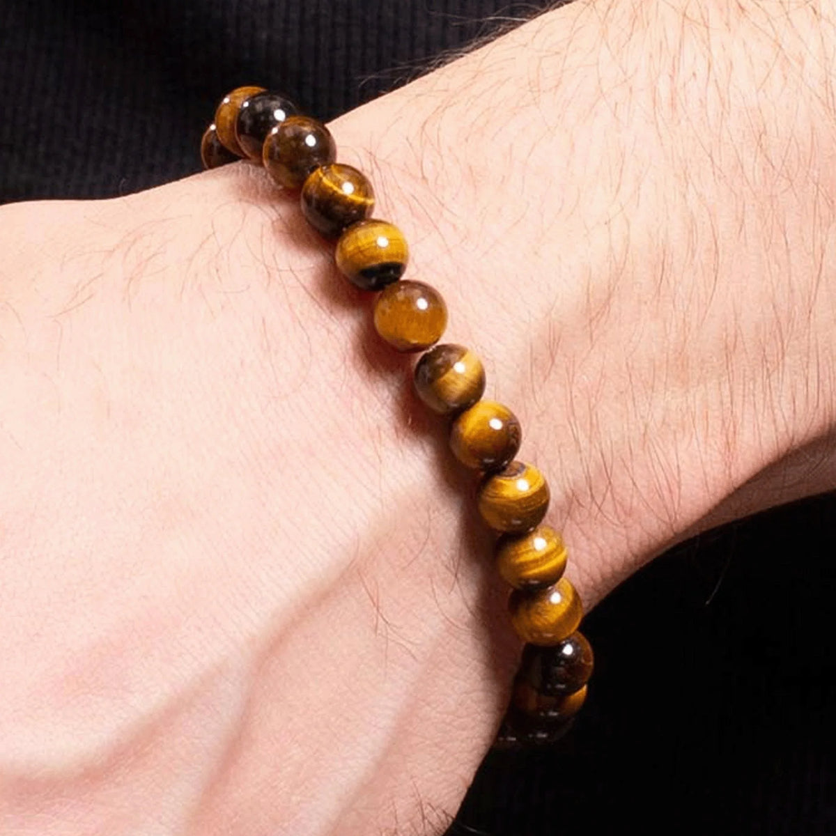 Tiger’s eye gemstone bead bracelet worn on a wrist.