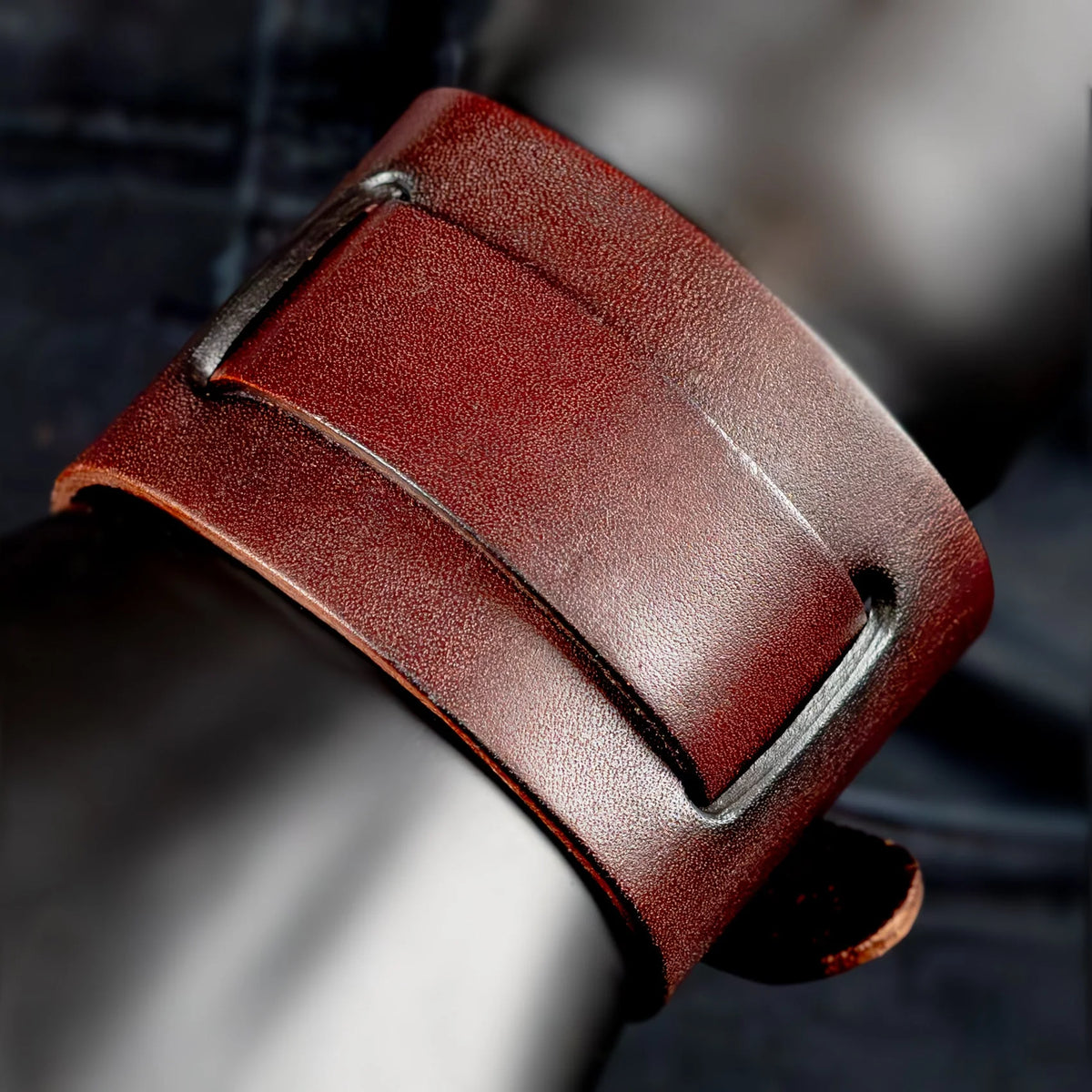 Reddish-brown leather cuff bracelet with metal hardware.