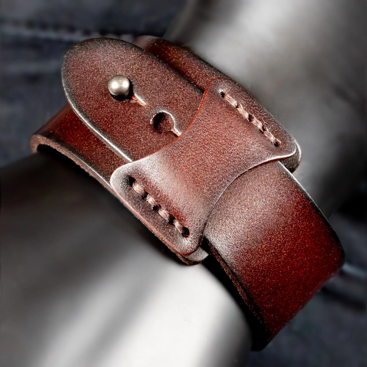 Leather watch strap with a metal buckle and stitching details.