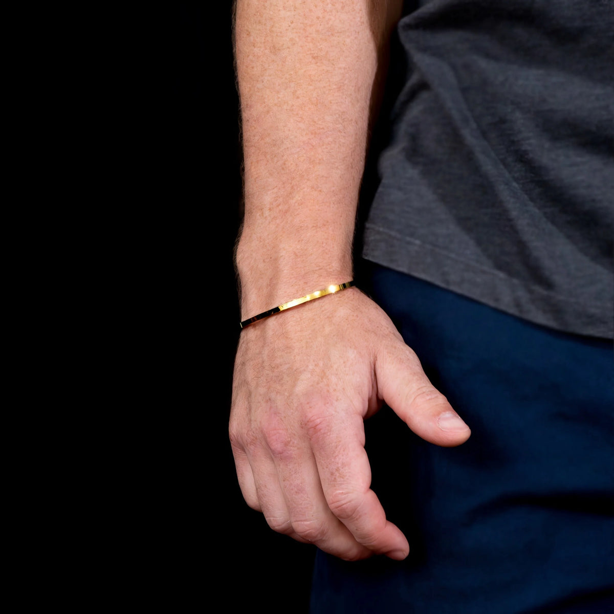 Gold bangle bracelet worn on a wrist.