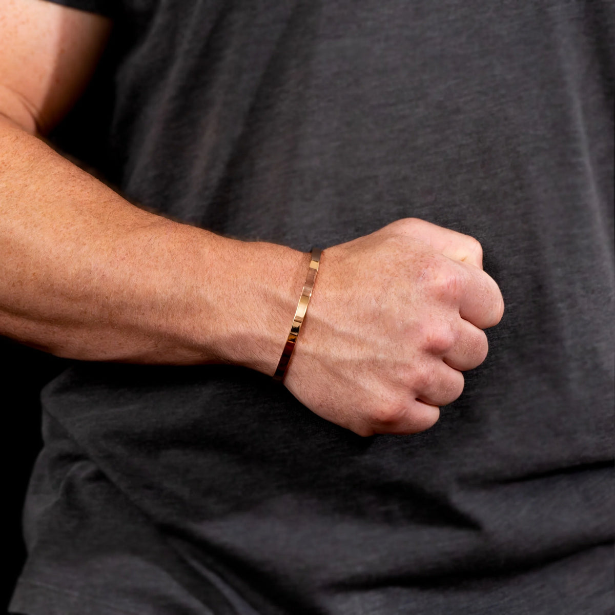 Gold bracelet worn on a wrist.