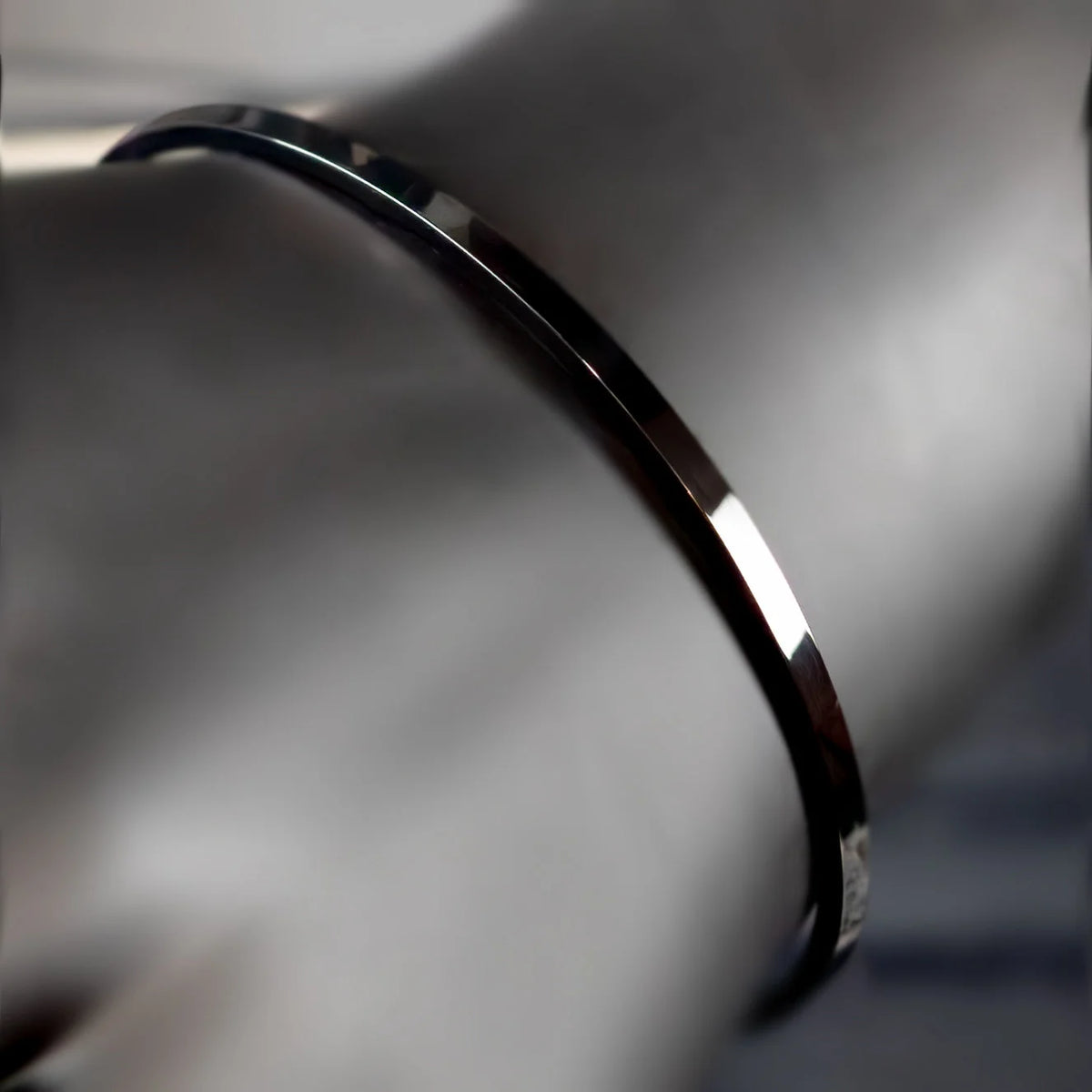 Curved, shiny metal band or ring with a polished surface.