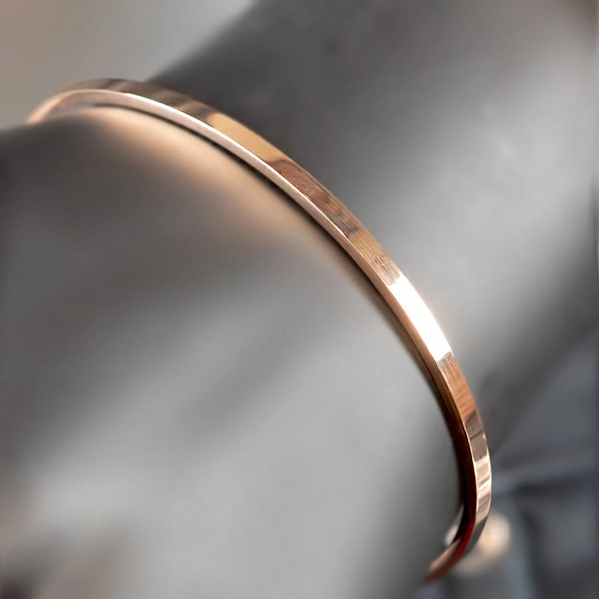 Thin, rose gold metallic bangle bracelet with a smooth, polished surface.