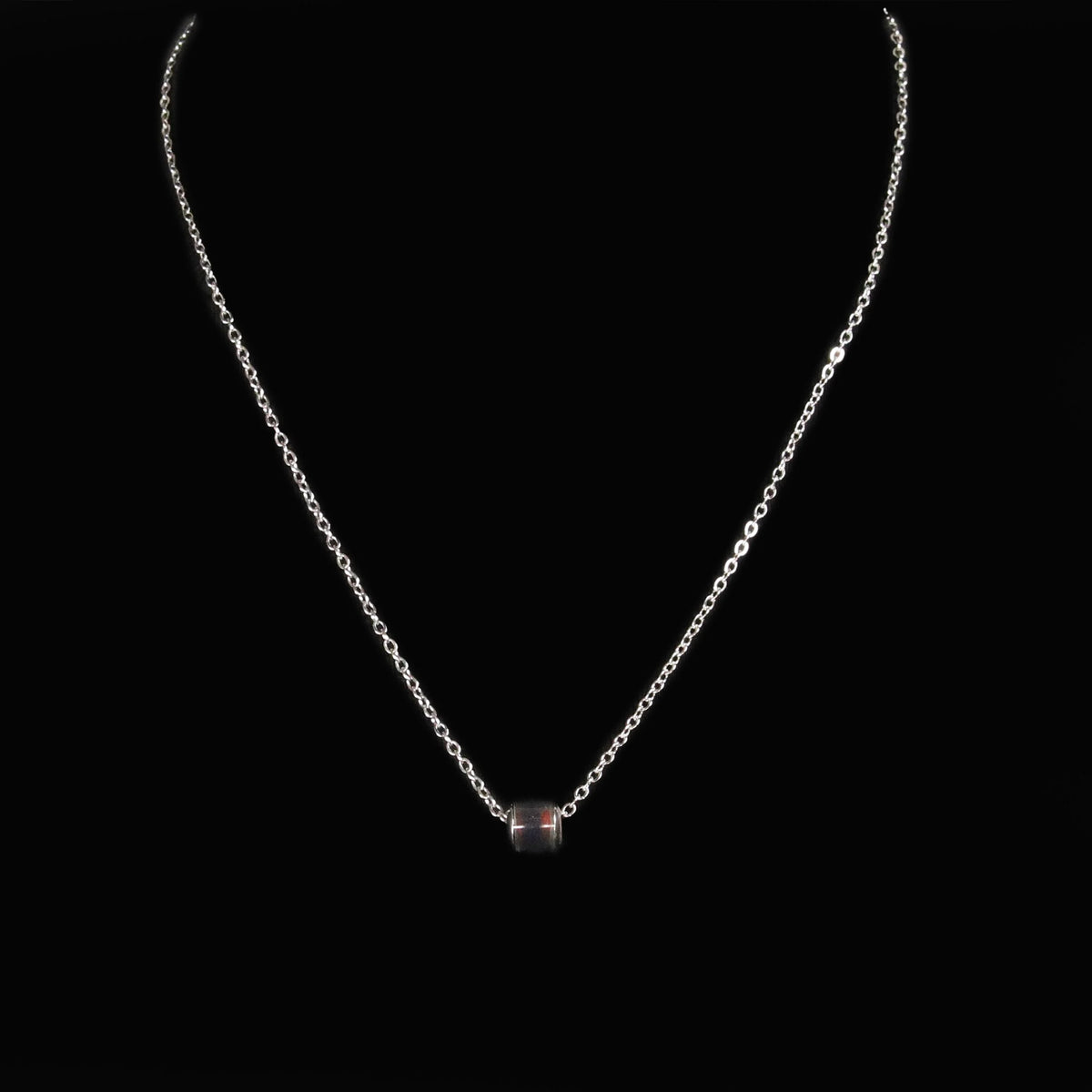 Silver necklace with a single dark bead or gemstone pendant.