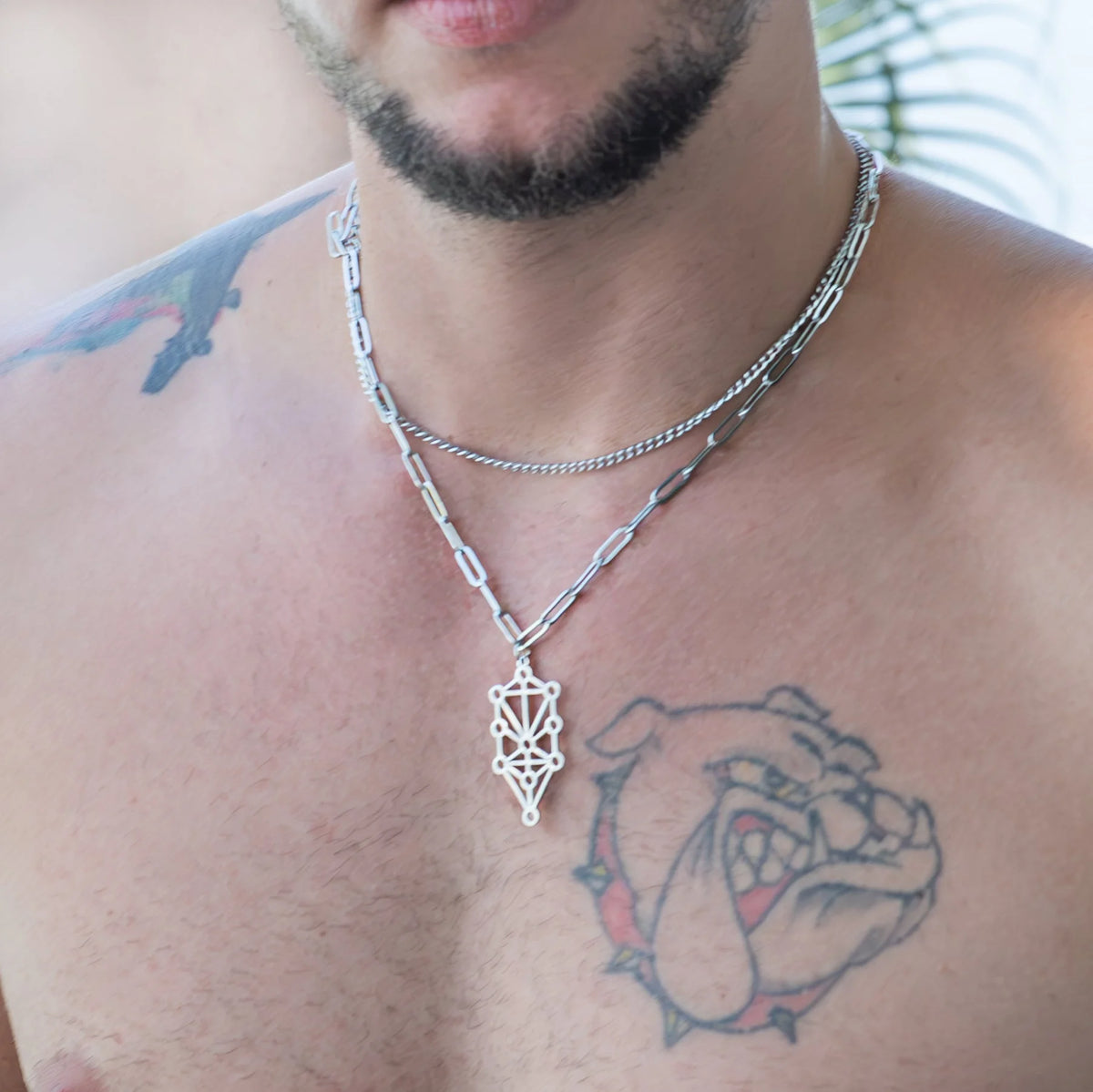 Chest tattoo of a bulldog’s face with a spiked collar.