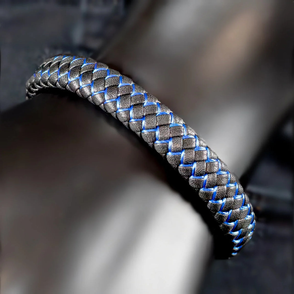 Braided metallic bracelet with silver and blue interwoven strands.