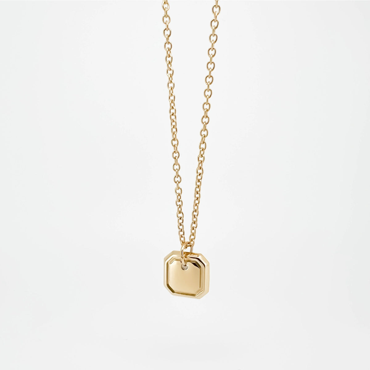 Gold-toned pendant necklace with a small square charm.